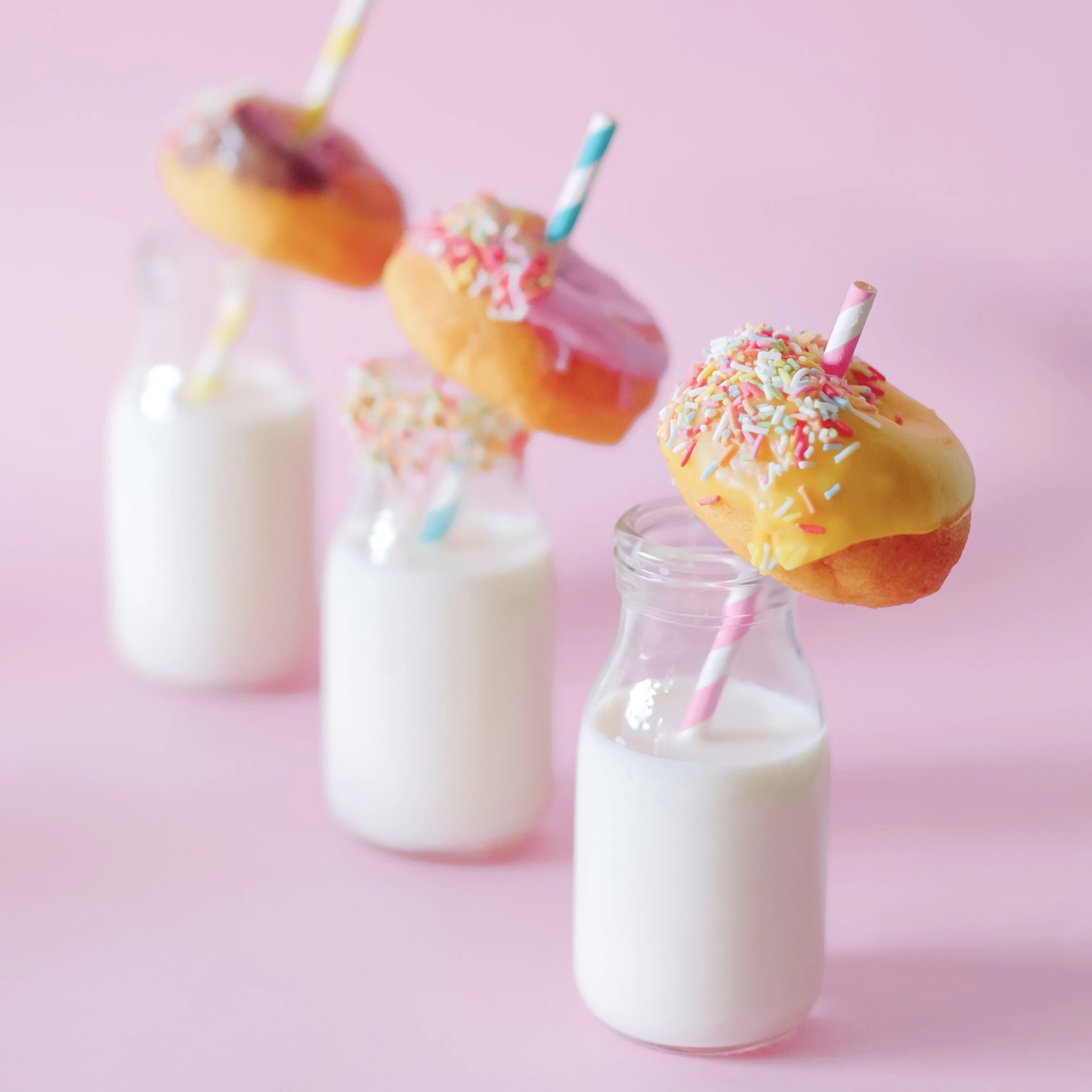 3 glasses of milk with a donut on the straw